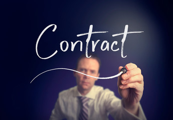 A businessman writing a Contract concept with a white pen on a clear screen.