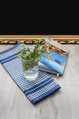 Still-life pen and diary for notes, wildflowers in a glass on a white-blue checkered napkin on a wooden background