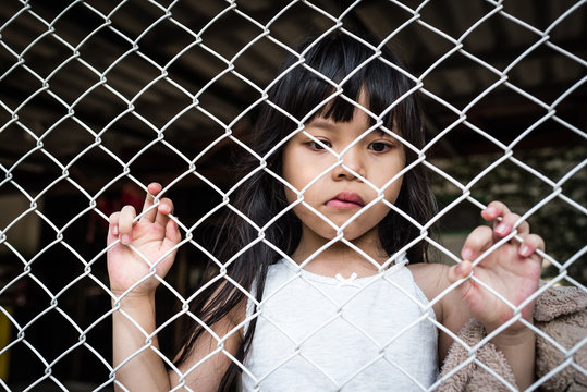 The sad Asian girl child, while sitting alone in cage was imprisoned make no freedom or lack of freedom