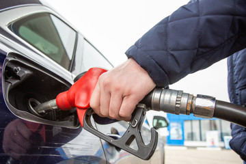 Fuelling gun inserted into the tank of blue car