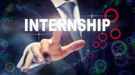 A businessman pressing a Internship business concept on a graphical display of cogs