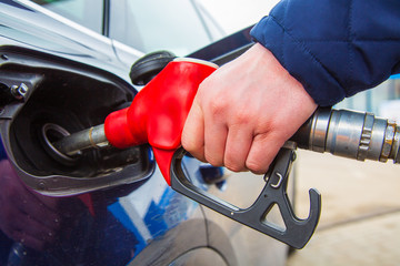 Fuelling gun inserted into the tank of blue car