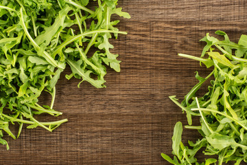 Fresh arugula flatlay isolated on brown wood background.