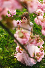 Look from above at charming young woman standing under blooming sakura tree