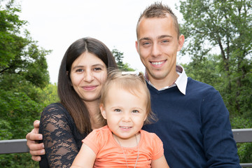 cheerful family of three with cute daughter girl father man and woman mother outdoor day