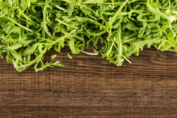 Fresh arugula leaves top view isolated on brown wood background.