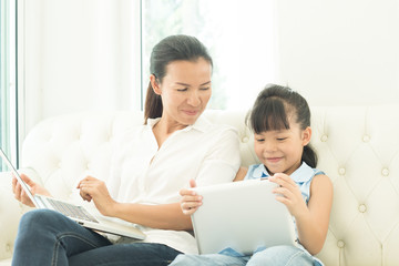 Fototapeta premium mother with daughter looking at Laptop on sofa