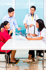 Asian doctor giving patient in office advice with X-ray photograph