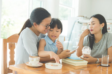 mother and daughter read a book drinking tea and cuddling in cafe