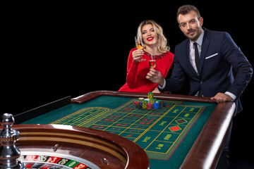 Beautiful and well dressed couple playing roulette in the casino