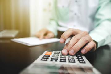 Man using calculator and writing make note with calculate in the office and Monitoring financial information.