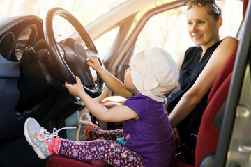 mother with child playing in the car steering wheel