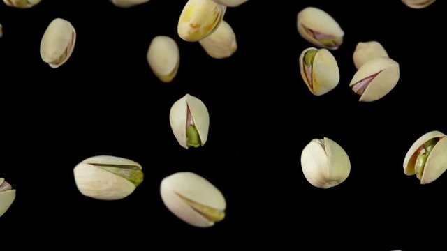 Close up pistachios are flying on a black background in slow motion