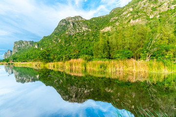 Pond and mountains under cloudy sky in Thailand