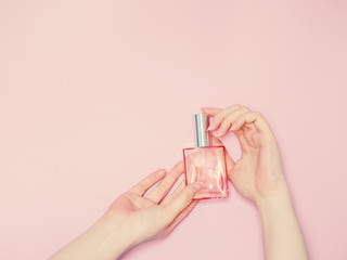 beauty for woman concept from beauty woman both hand show and hold perfume bottle in hand with isolated pink pastel background