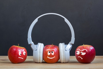 envy Creative concept. Abstract image with apples. One Apple in headphones standing in crowd stands...