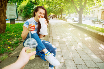 woman eating croissant on street. food to go