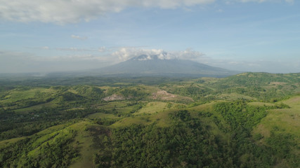 Fototapeta premium Aerial view of mountain valley with hillscovered forest, trees, mount Iriga. Luzon, Philippines. Slopes of mountains with evergreen vegetation. Mountainous tropical landscape.