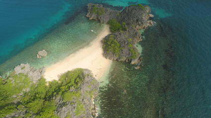 Aerial view island with sand beach and turquoise water in blue lagoon among coral reefs, Caramoan Islands, Philippines. Landscape with sea, tropical beach.