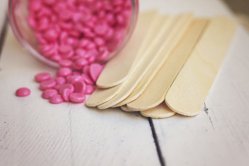 depilatory pearly pink  solid wax beans and wooden stick wood on wood background