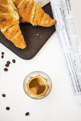 Espresso coffee glass with croissants and newspaper.top view