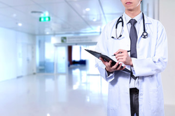 Smart male doctor wearing a medical suit hang on stethoscope and holding with blurred hospital in background. Doctor concept.