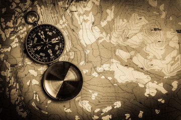 Manual compass on a topographical map with vintage look