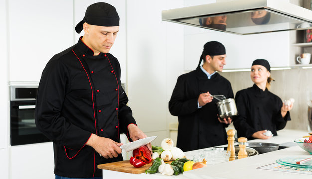 Female and male  cooks wearing black uniform working on kitchen