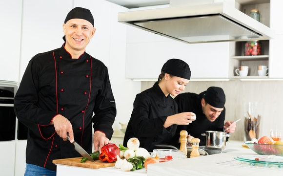 Team of  woman and man chefs in black uniform preparing food