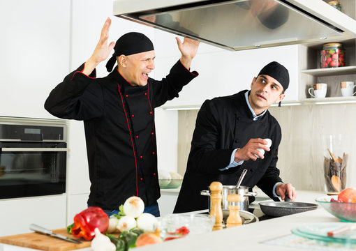 Men kitchener in uniform are emotional cooking salad in the kitchen