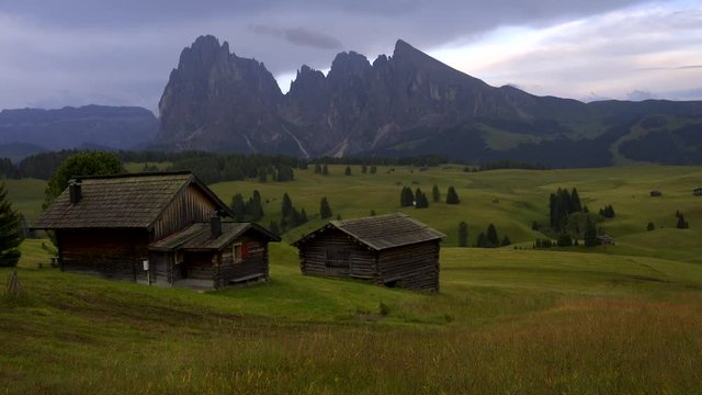 Video of the Sassolungo mountains on the Italian Alps Dolomites with wood houses on the foreground