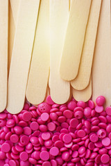 depilatory pearly pink  solid wax beans and wooden stick background