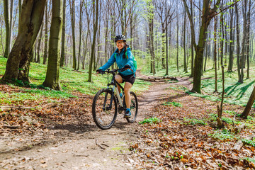 Naklejka premium young woman ride bicycle in forest by trail