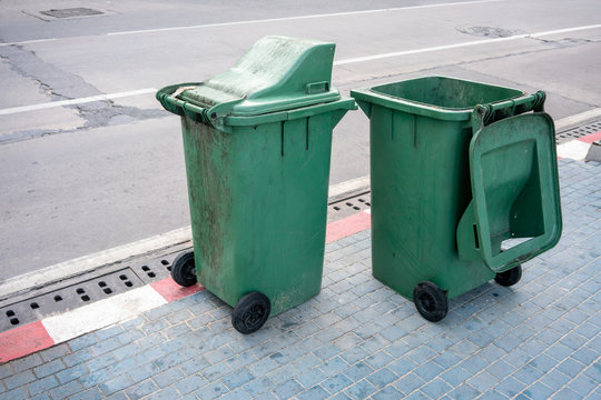 Two green public dirty trash can on street