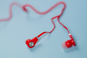 Red new earphone with cable on blue paper background