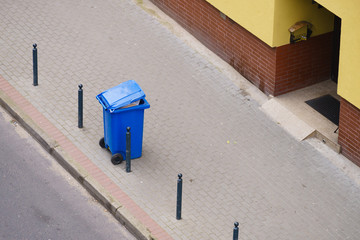 Blue trash can on street pavement