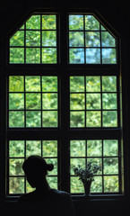 Window of church and silhouette woman with flower.