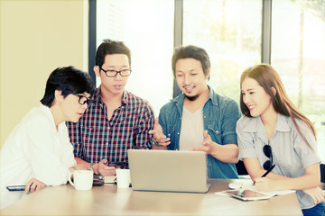 Smart handsome asian businessman  or student explaining his project to asian Team group freelancer in casual suit at coffee shop cafe. Business and Office Concept.