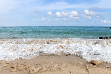 Foamy waves of azure ocean crashing on white sand coast line. Bali, Indonesia.
