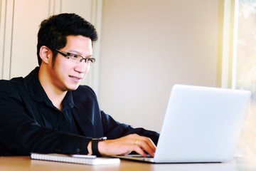Smart handsome asian businessman in casual suit using laptop and smart phone for working at modern office or coffee shop cafe. Business and Office Concept.