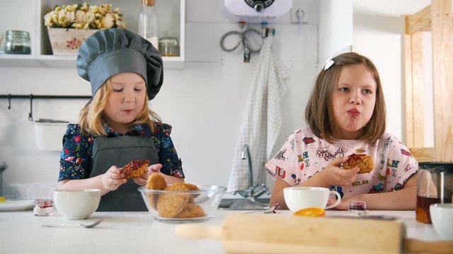 Two girls eats cookies with jam prepared with their own hands