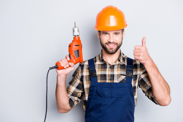 Portrait of joyful cheerful repairer in protective hard hat, overalls, shirt with bristle showing...