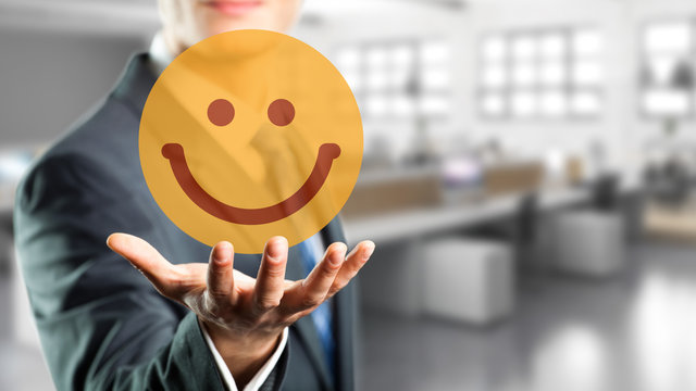 Geschäftsmann präsentiert lächelnden Smiley vor Bürohintergrund