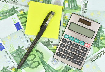 Calculator, pen, note paper and euro money