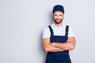 Portrait with copyspace, empty place for advertisement of cheerful positive deliver in blue uniform looking at camera, having his arms crossed, isolated on grey background - obrazy, fototapety, plakaty
