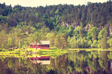 Obraz premium wooden cabin in forest on lake shore, Norway