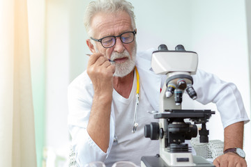 Doctor older or seriously scientist working with a microscope in Laboratory.