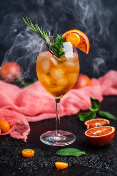 Cocktail with orange juice and ice cubes. Glass of orange soda drink on dark background 