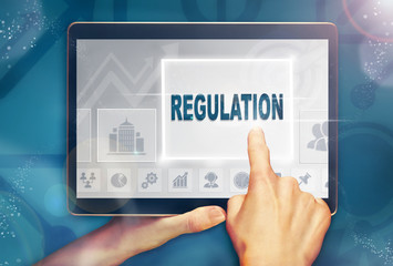 A hand selecting a Regulation business concept on a computer tablet screen with a colorful...