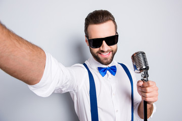 Self portrait of stylish elegant singer wearing bowtie shirt suspenders shooting selfie on front...